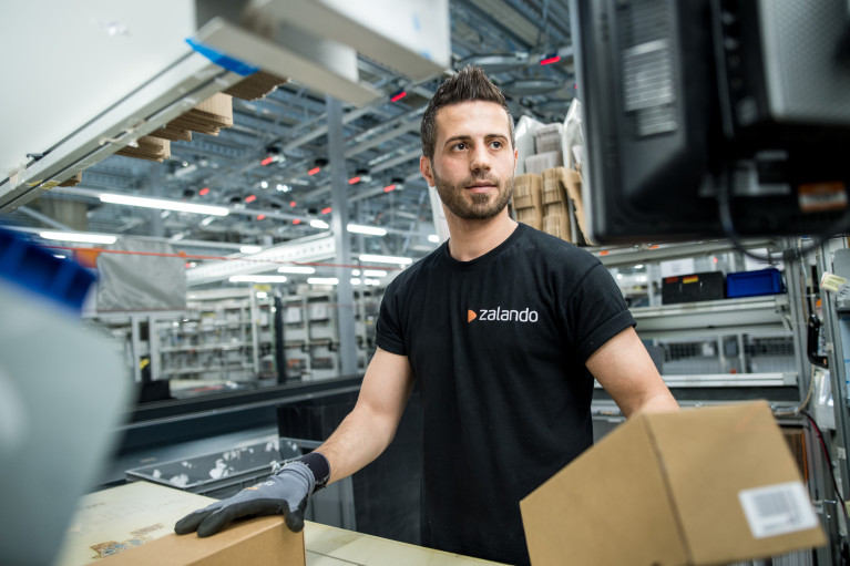 Logistics employee in black Zalando shirt handling boxes