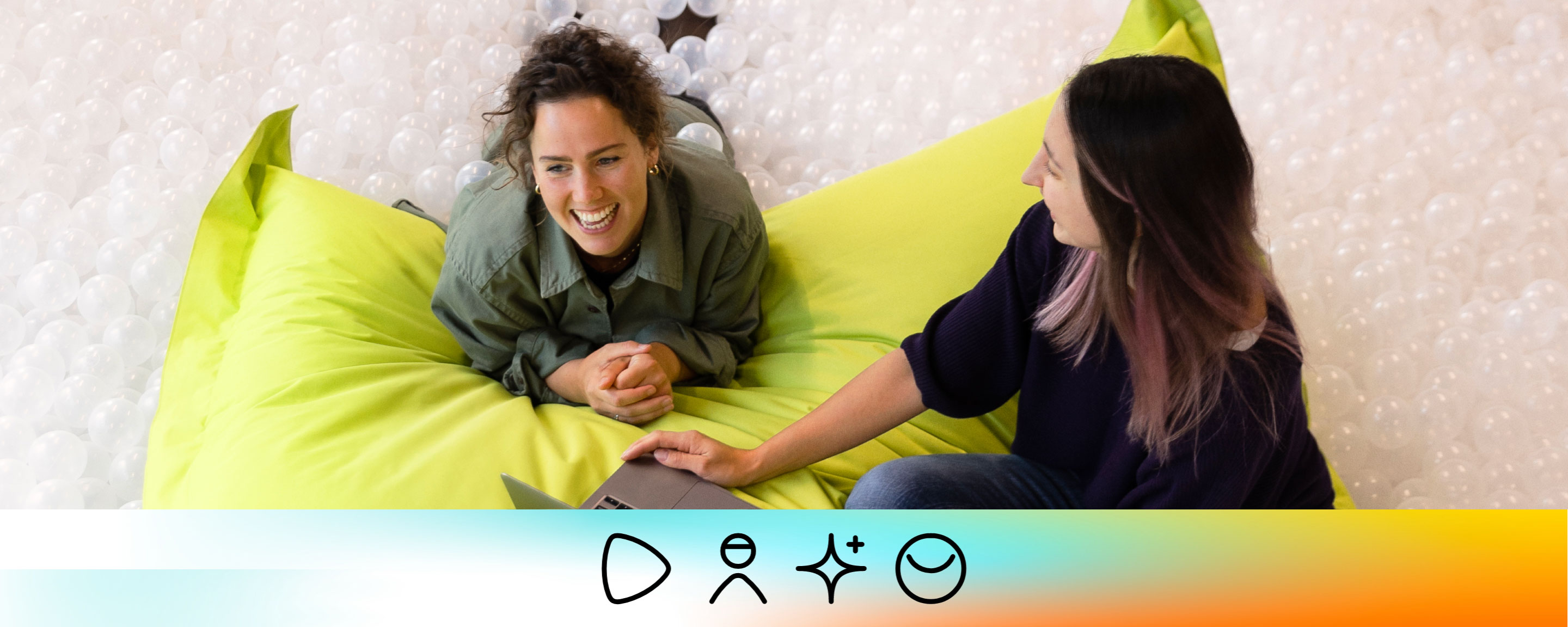 Two Zalando employees working together, sitting on a big pillow in a ball pool