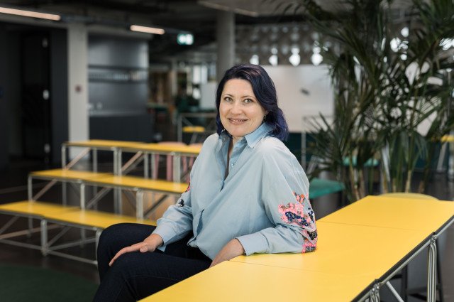 Galina Charni sitting at a yellow table smiling at the camera