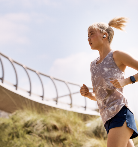 Woman running outdoors, wearing a smartwatch an ear pods