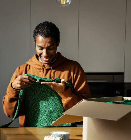 Man looking at green fabric next to an open cardboard box