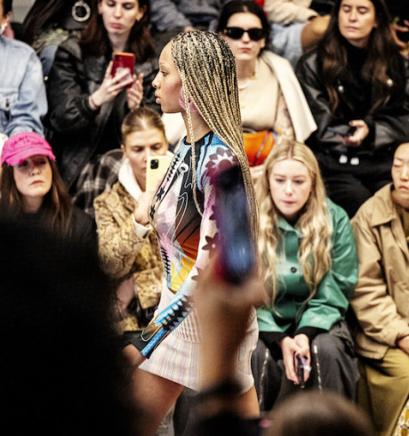 Fashion model on the runway; audience in the background