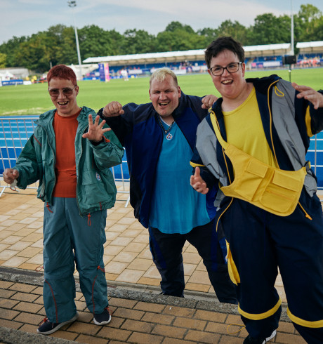 Three athletes presenting sports fashion to the camera; inside a stadium