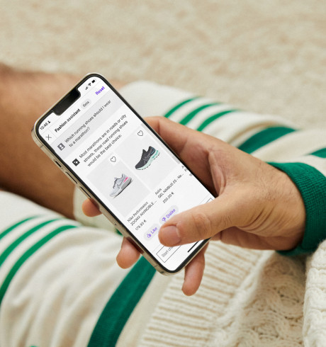 A Zalando customer sitting on the floor looking at the Zalando fashiobn assistant on his mobile phone; only hand and part of their legs are visible
