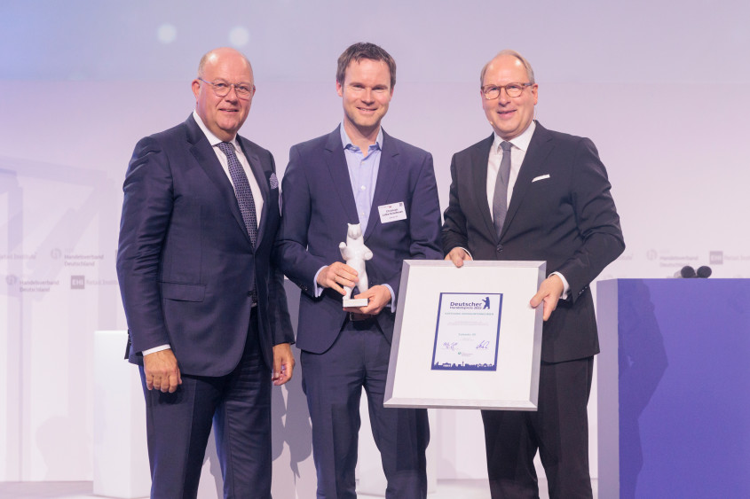 HDE Präsident Alexander von Preen, Christoph Lütke Schelhow and HDE Hauptgeschäftsführer Stefan Genth posieren auf der Bühne mit dem Award