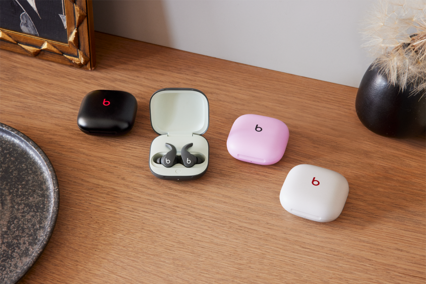 Four differently coloured cases of Beats ear pods arranged on a wooden tabletop
