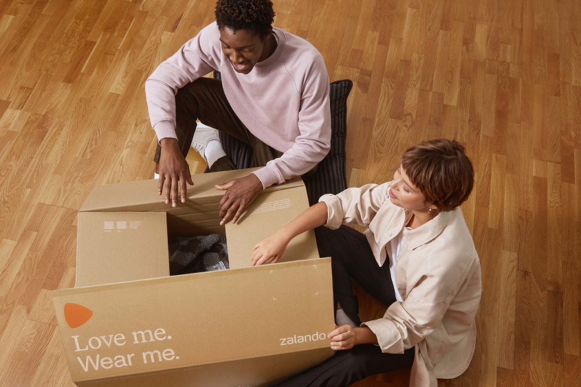 A man and a woman open a big Zalando box together.