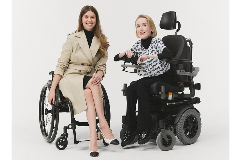 Two well-dressed women in wheelchairs posing for the camera