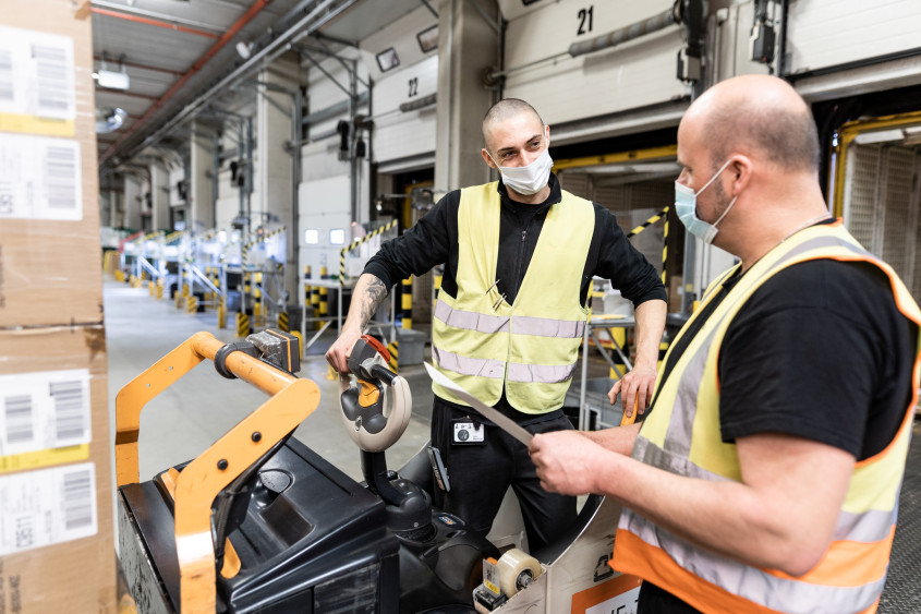 Two men working together in a logistics facility aisle