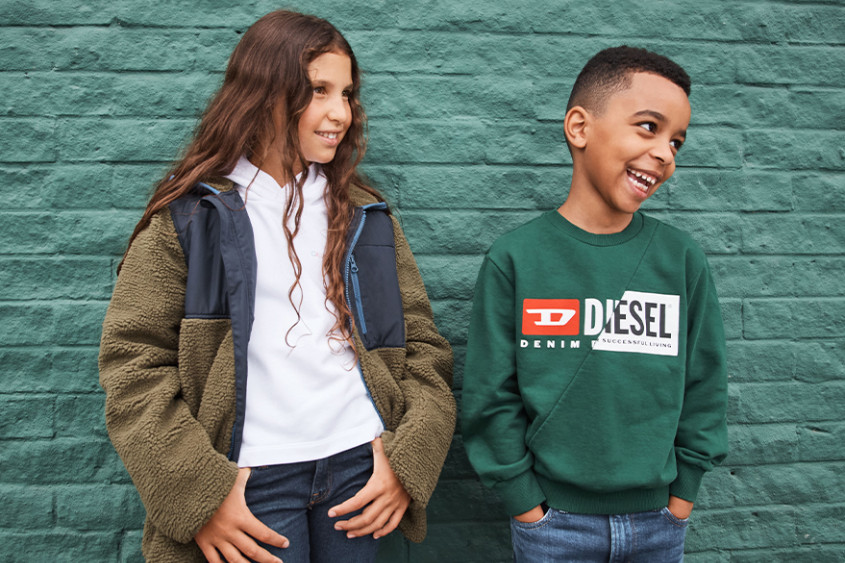 Girl and Boy posing in front of a green wall