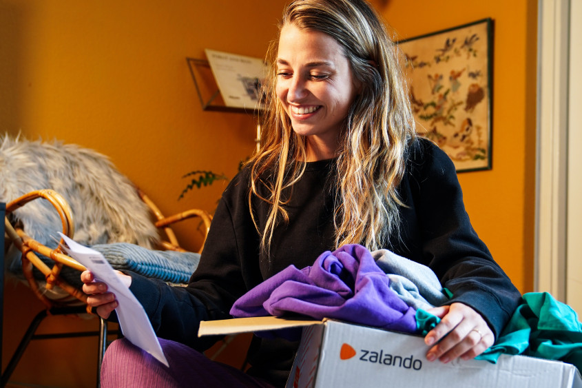 Woman sitting on the floor, unpacking Zalando parcel