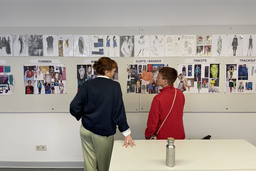Athlete and designer discussing design information pinned onto a whiteboard