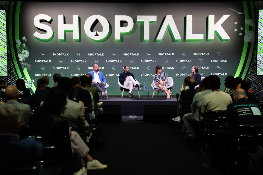 Four people sitting on stage in a panel discussion; the backdrop reads SHOPTALK