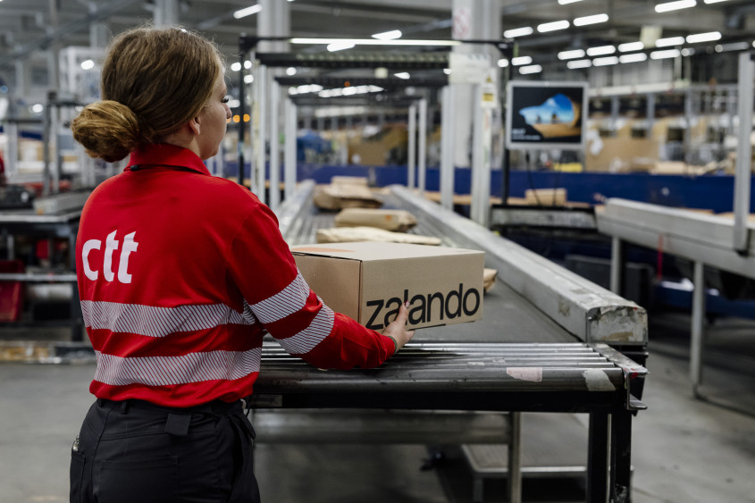 A ctt employee taking a Zalando parcel from a warehouse conveyor belt