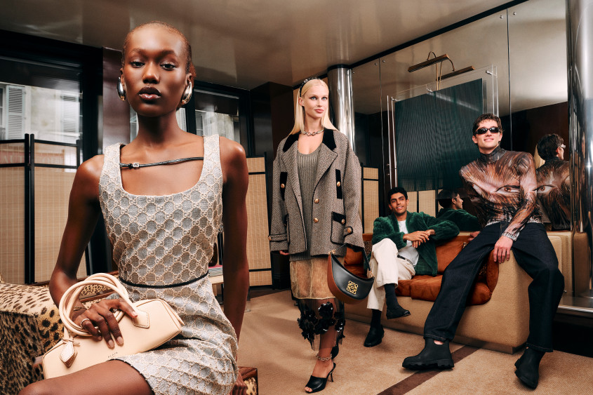 A group of young people in trendy outfits; the two men loungin on the sofa, one of the women perched on an armchair