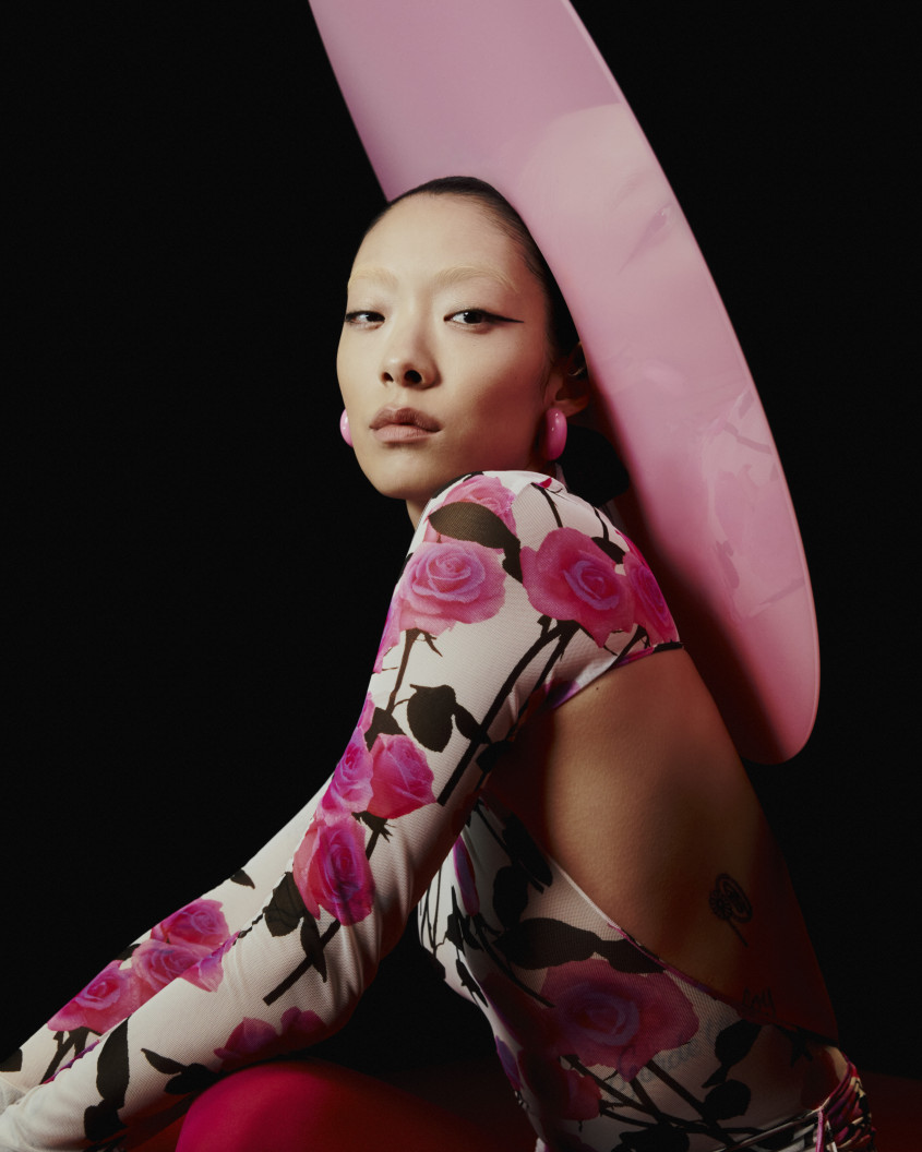 Rina Sawayama crouching down in a pink outfit with a large hat for Zalando