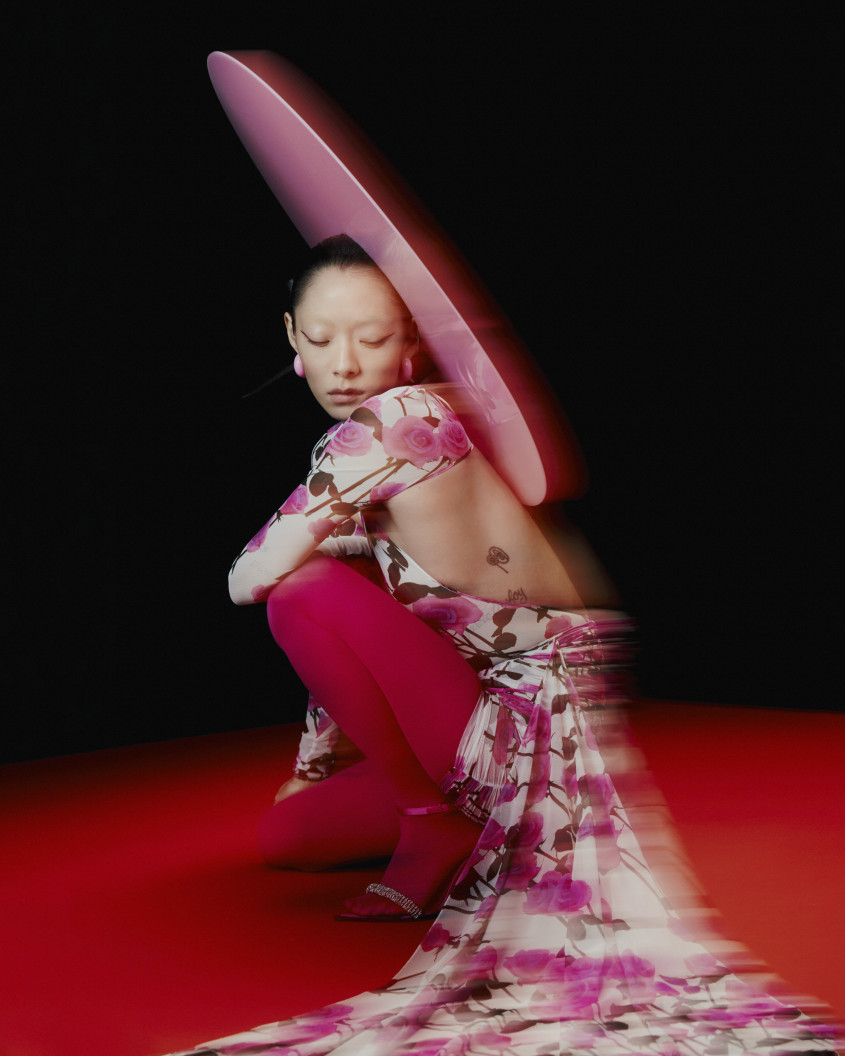 Rina Sawayama crouching down in a pink outfit with a large hat for Zalando
