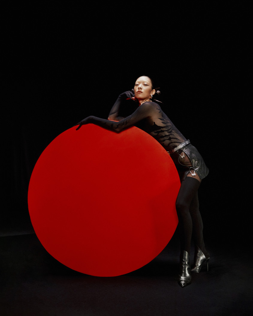 Rina Sawayama in a black outfit standing next to a red circle for Zalando