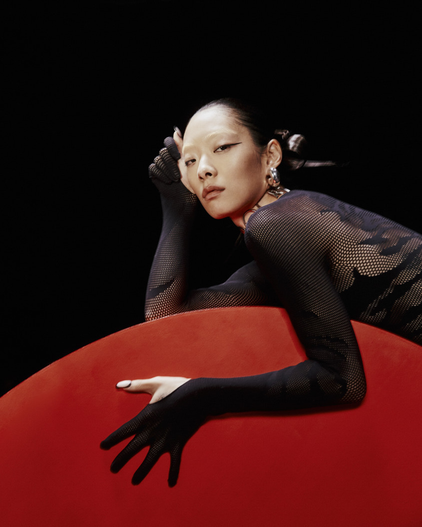 Rina Sawayama in a black outfit on a red couch for Zalando