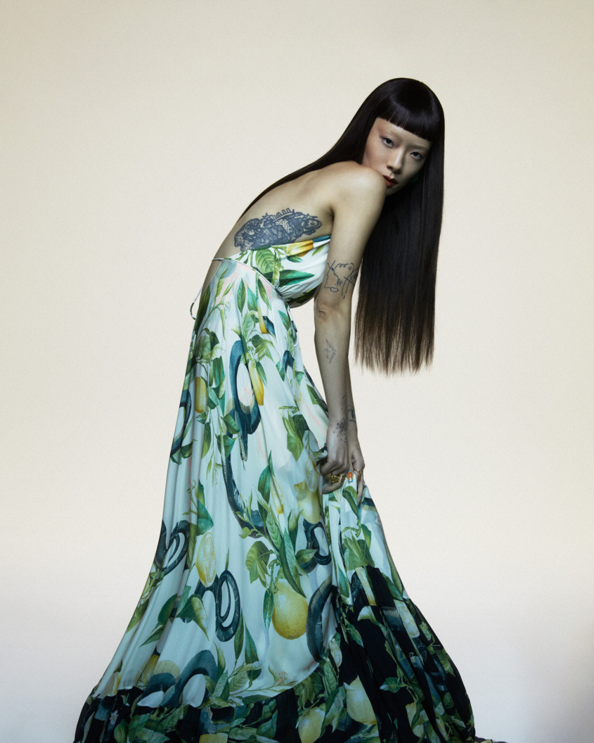 Rina Sawayama slumped over in a colorful dress for Zalando