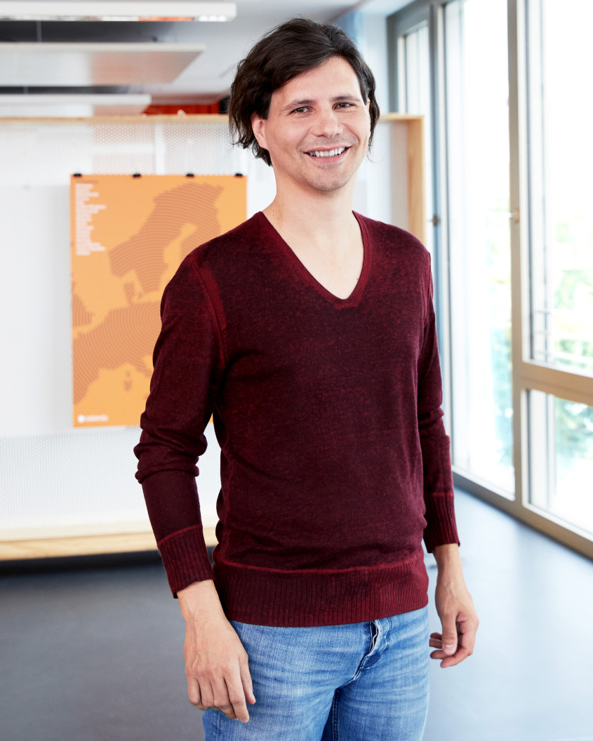 A smiling man in front of windows