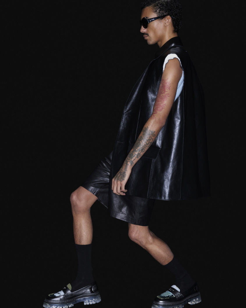 Fashion model wearing chunky black shoes, black socks and clothes, and sunglasses