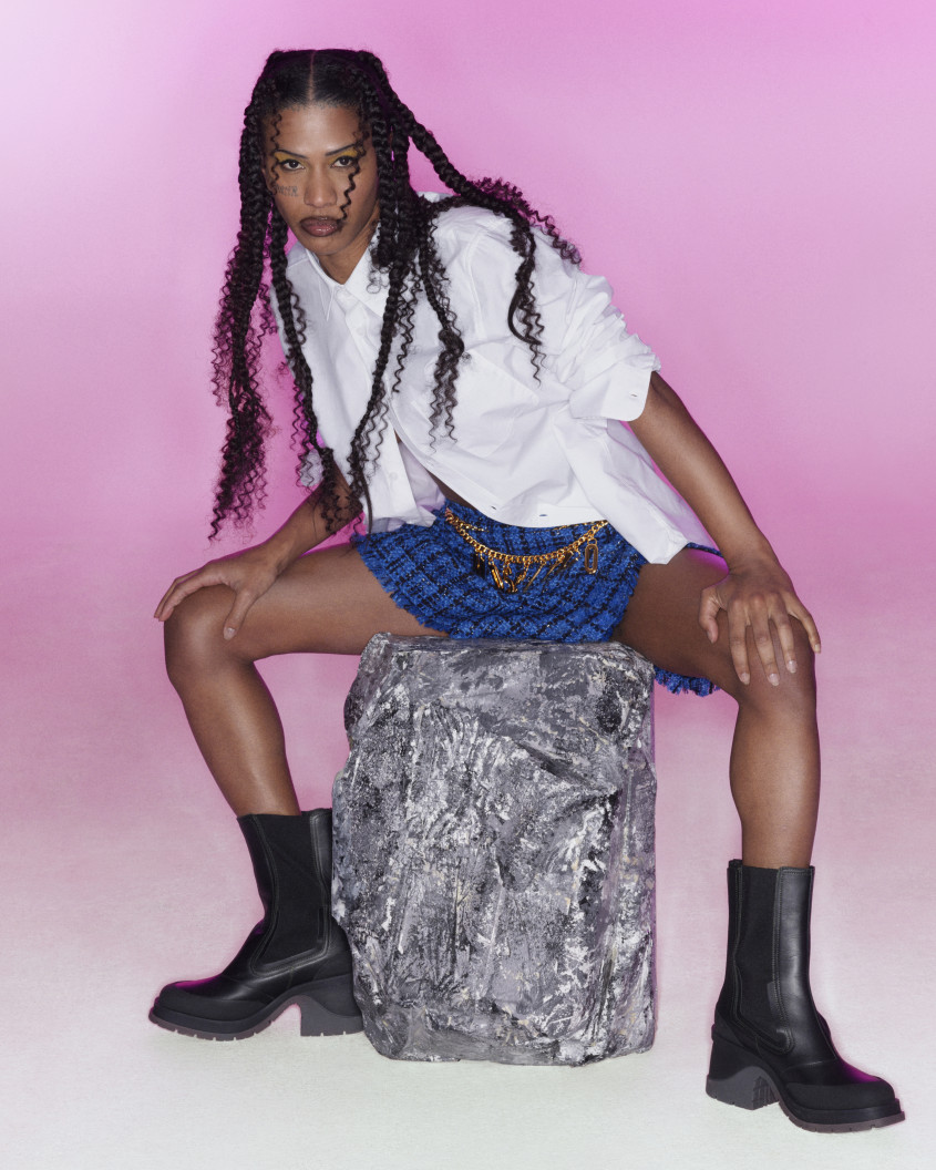 Fashion model wearing chunky black boots, blue miniskirt and a white blouse
