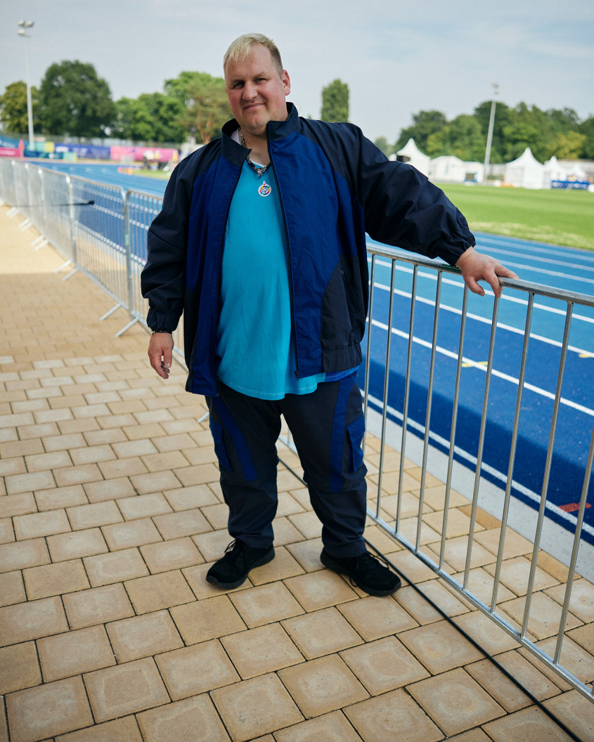 Male athlete in casual sportswear standing in front of a blue racetrack