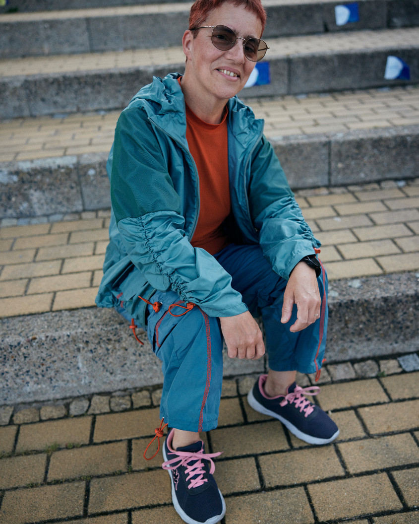 Female athlete wearing sunglasses and casual sportswear sitting on stone steps