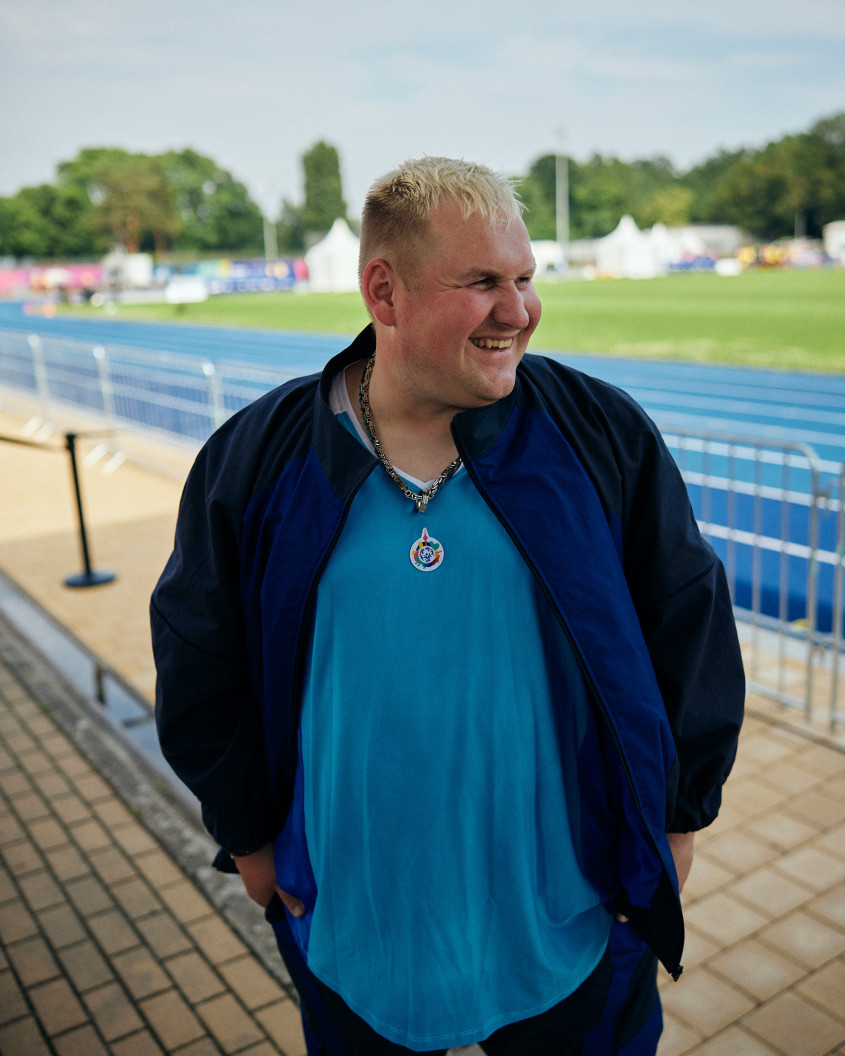 Male athlete in casual sportswear standing in front of a blue racetrack