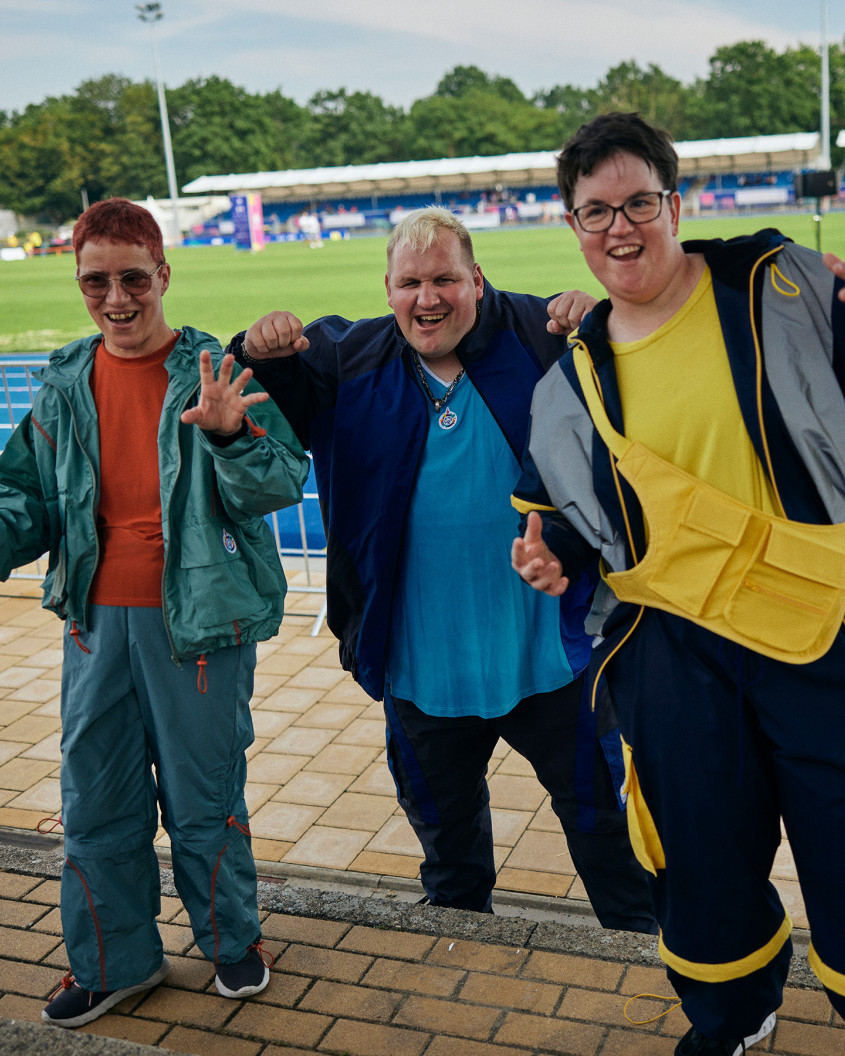 Three athletes presenting sports fashion to the camera; inside a stadium