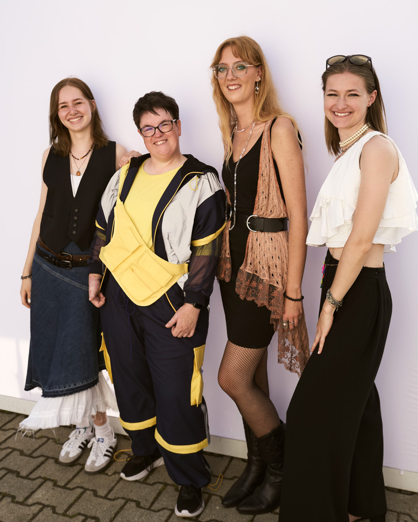 Female athlete wearing casual sportswear flanked by three designers smiling for the camera