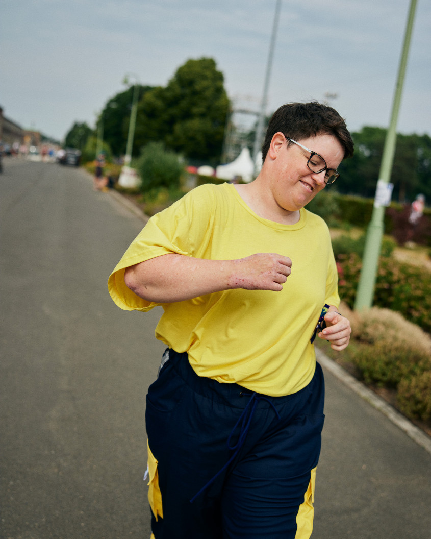 Female athlete in blue and yellow casual sportswear running along a path