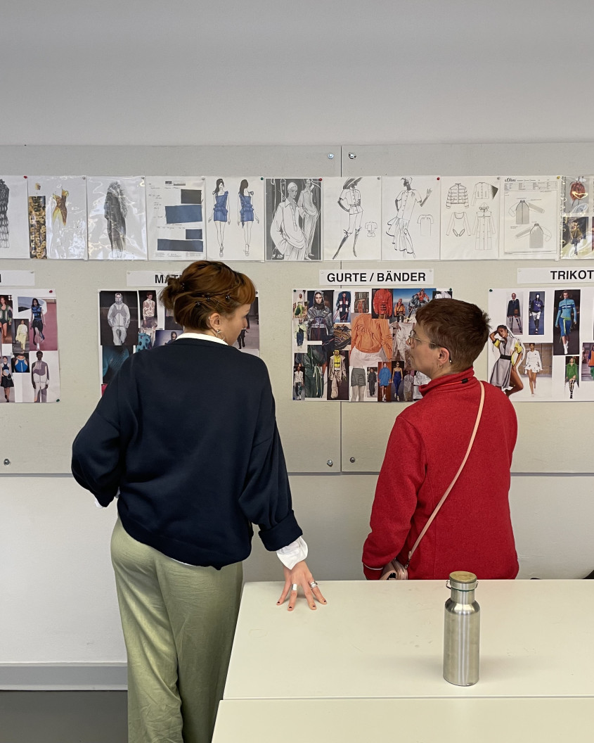 Athlete and designer discussing design information pinned onto a whiteboard
