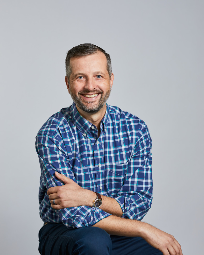 Portrait of Peter Circ sitting on a stool, smiling at the camera