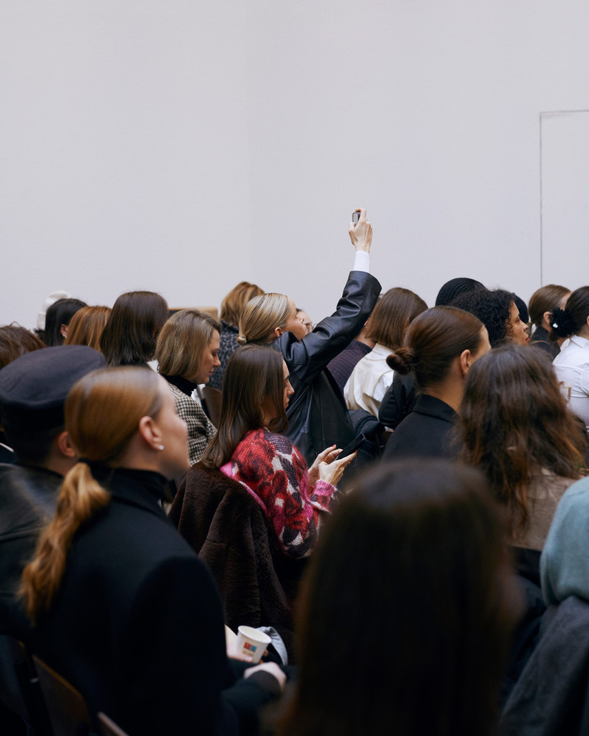 Audience during panel discussion from behind; one person holding up their phone filming