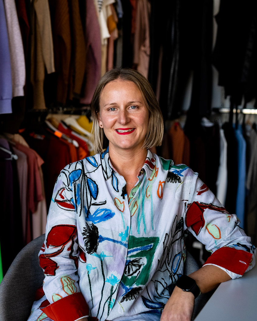Jemma Garner sitting in front of clothes racks