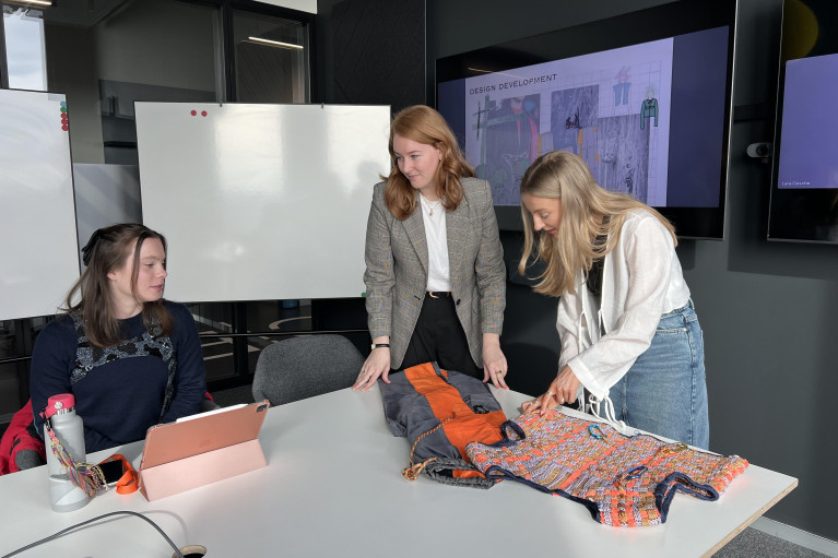 Two young female students present their prototype to a GFF representative