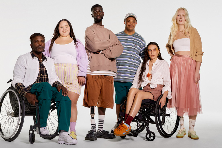 Six people modelling adaptive fashion; two of them are sitting in a wheelchair, two have visible prosthetic legs