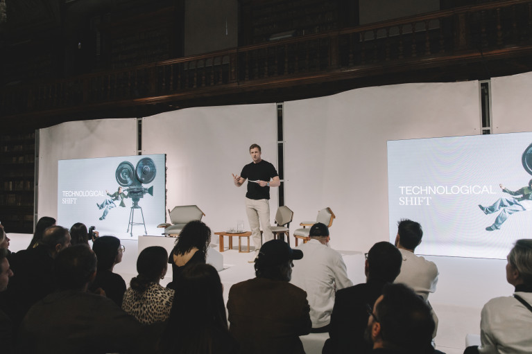 David Schneider speaking on stage; the screens behind him read: Technological Shift