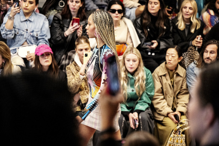 Fashion model on the runway; audience in the background
