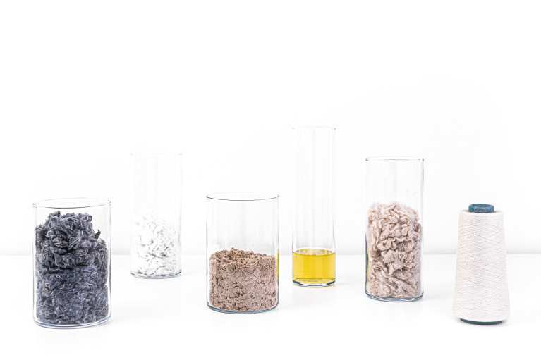 Four different materials in glass containers plus one spool of thread