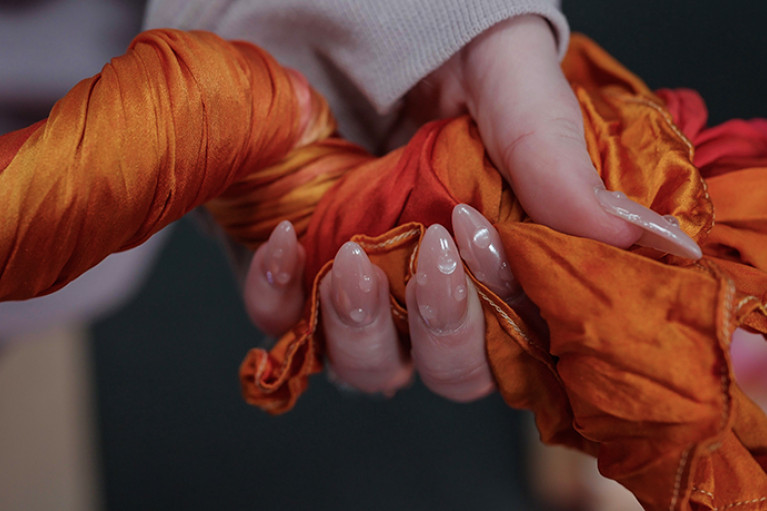 a twisted strand of orange silk held in hand