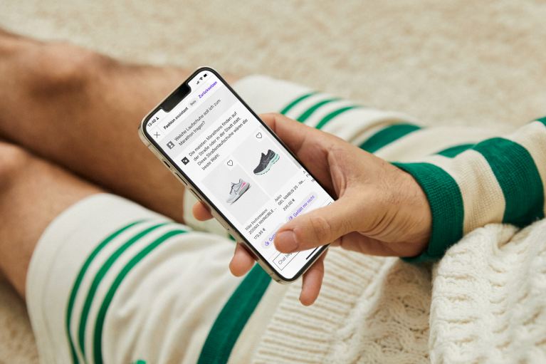 Auf dem Boden sitzende Person, die auf dem Smartphone den Zalando Fashion Assistant nutzt; nur Hand und Beine sind zu sehen
