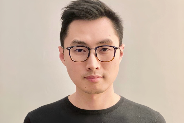 Portrait of Ray Cao in a black long sleeve and dark-rimmed glasses
