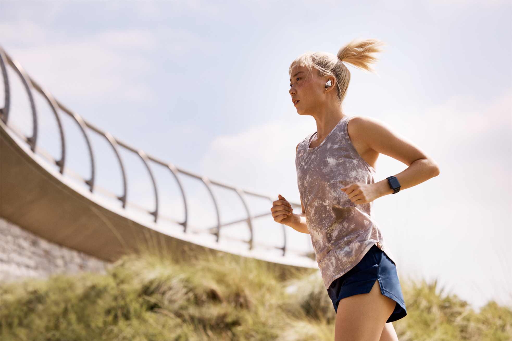Woman running outdoors, wearing a smartwatch an ear pods
