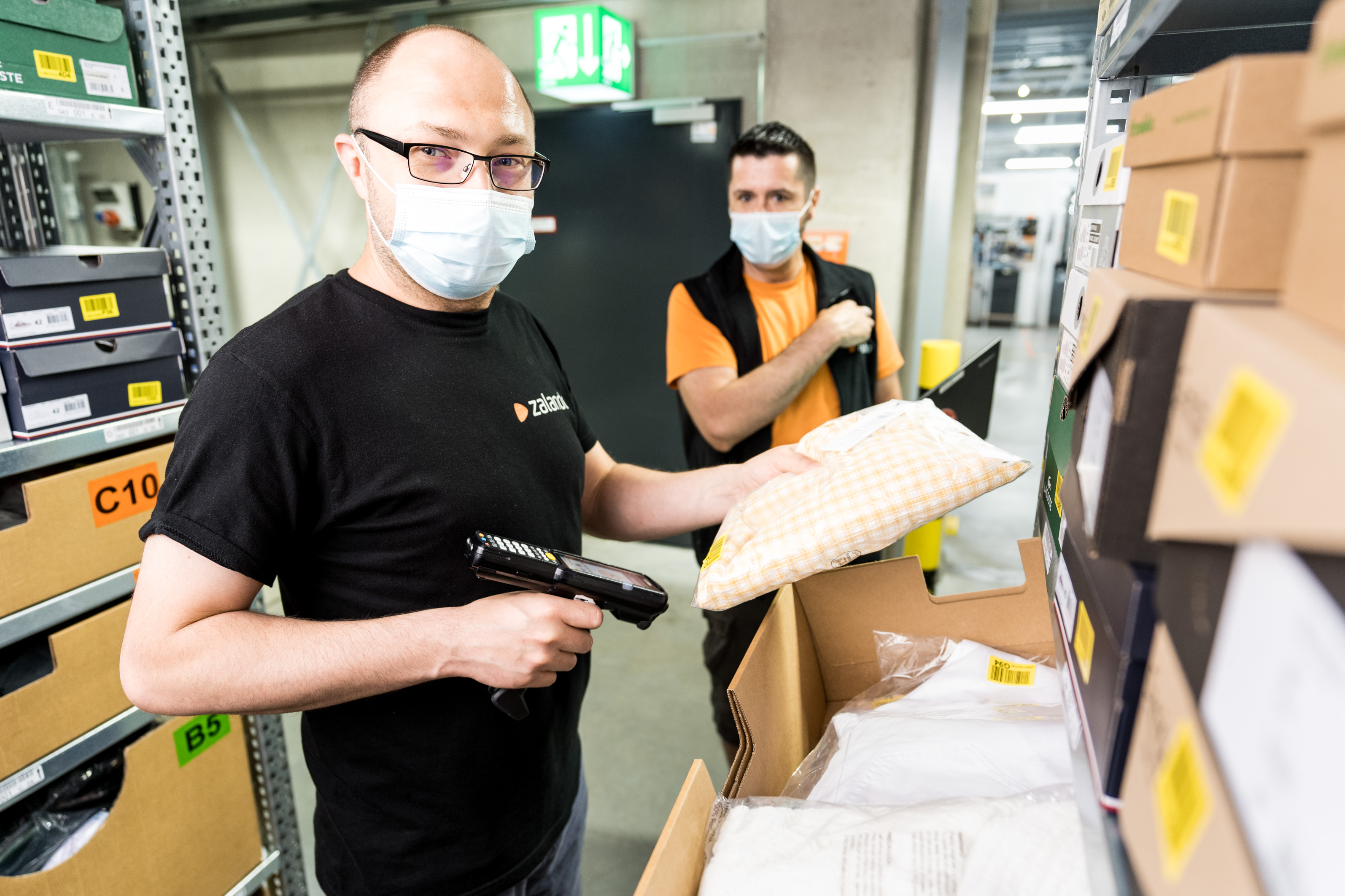 Two logistics employees scanning products and looking at the camera