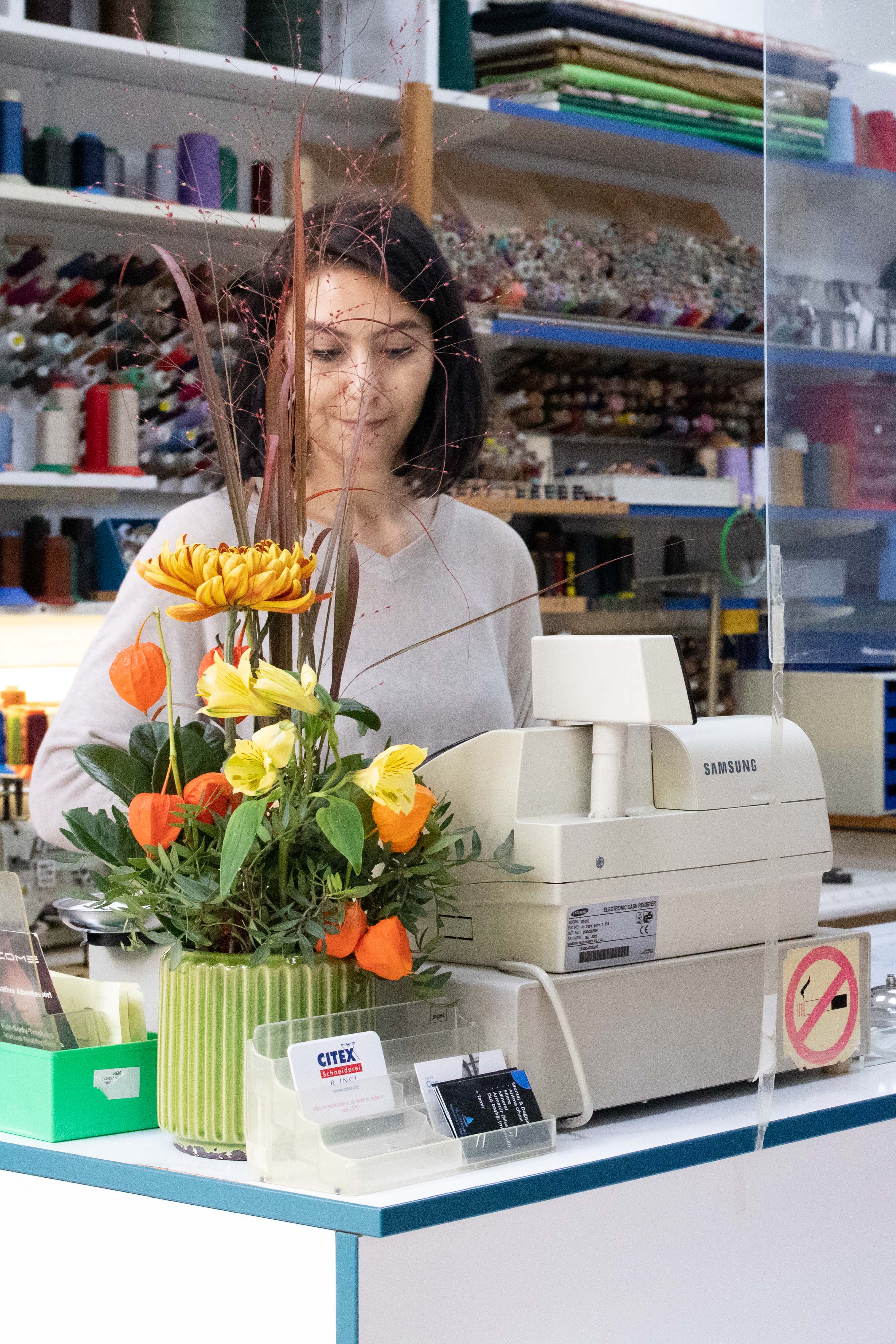A woman behind a cash register of a tailor's shop