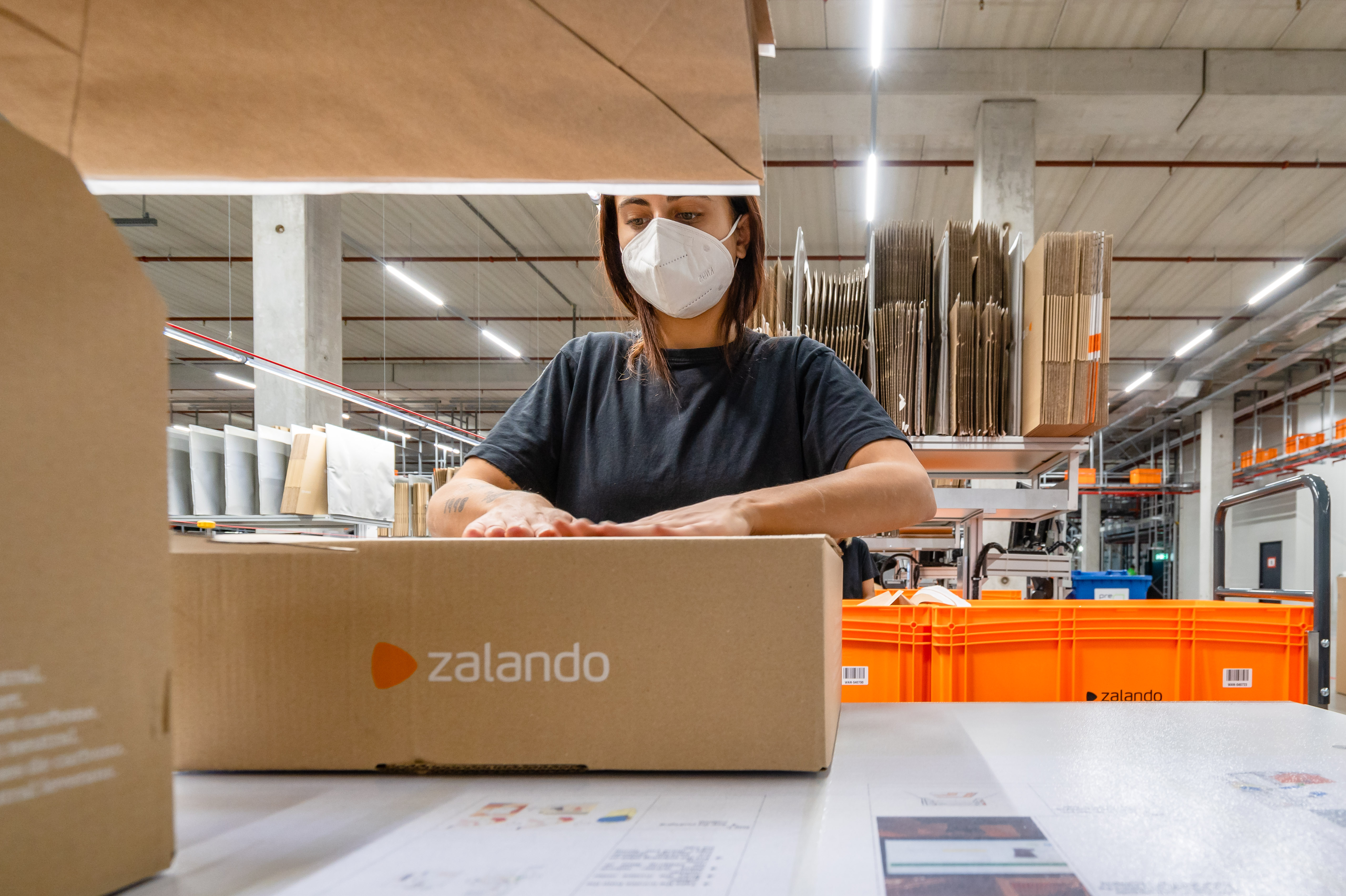 Employee at a fulfillment center closing a Zalando-branded parcel