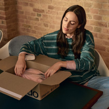 A woman sitting comfortably at a table unpacking a Zalando parcel